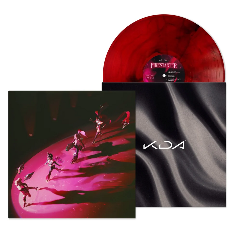 A high-angle view of several dancers performing on a glossy pink circular stage under dramatic red and pink lighting, with long shadows stretching across the dark background. The inner sleeve is a black satin sheet rippling with "KDA" logo over the top in the center. The record is sticking out of the top of the inner sleeve, with a red variant peppered with black smoky accents.